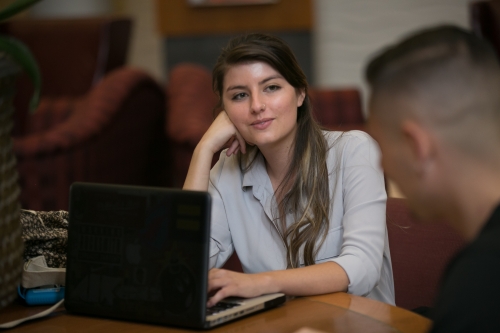 student leans on desk in front of laptop