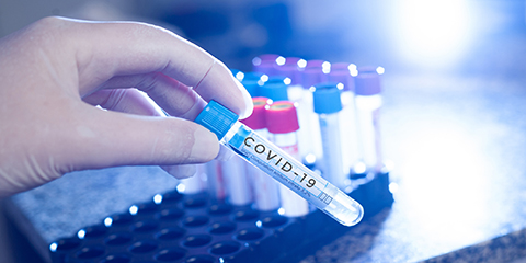 Lab worker handling test tube labeled "COVID-19"
